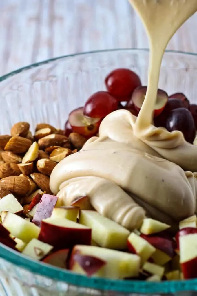 dressing being poured on chicken salad ingredients