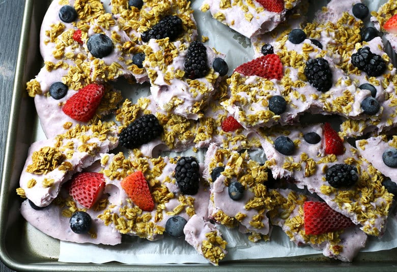 This triple berry granola frozen yogurt breakfast bark is perfect for busy mornings. It's like eating a make-ahead breakfast parfait popsicle and is great for feeding a crowd! Bark cracked in a sheet pan.