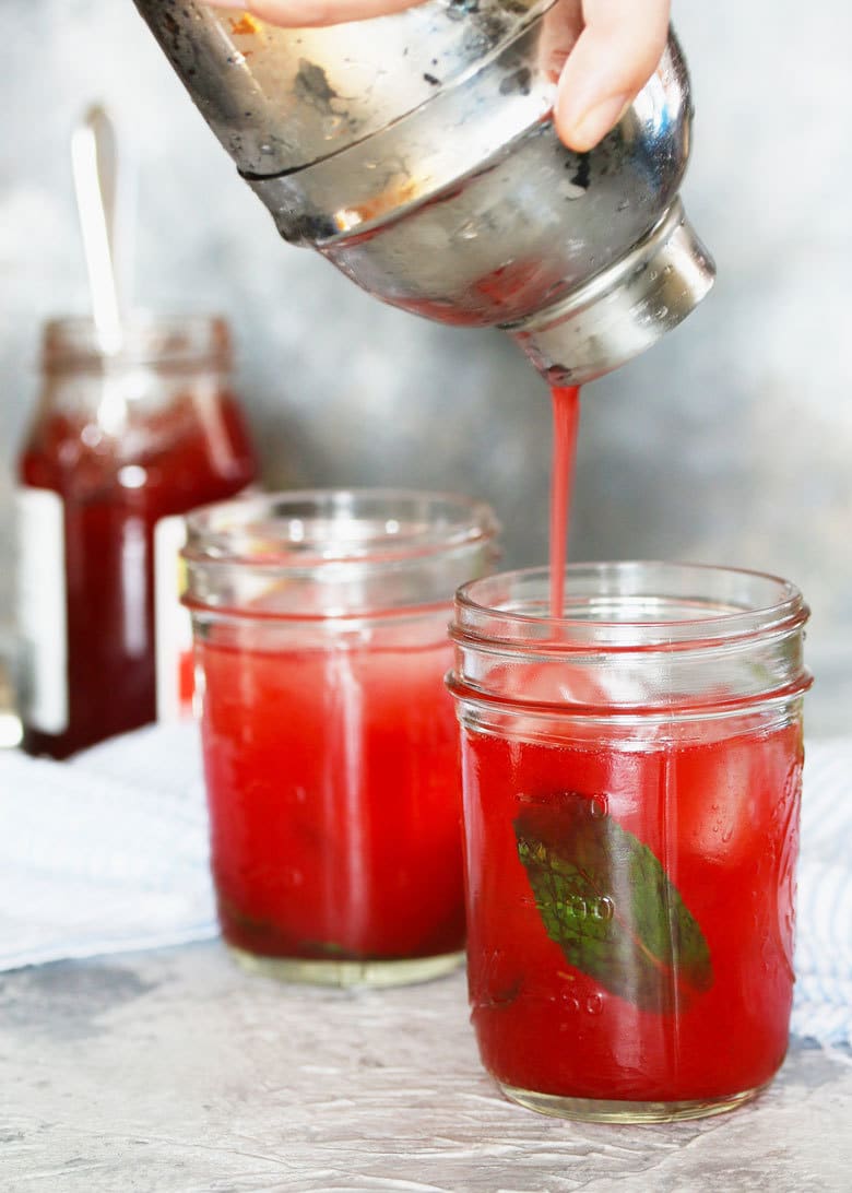 mint strawberry jam cocktail being poured from a cocktail shaker