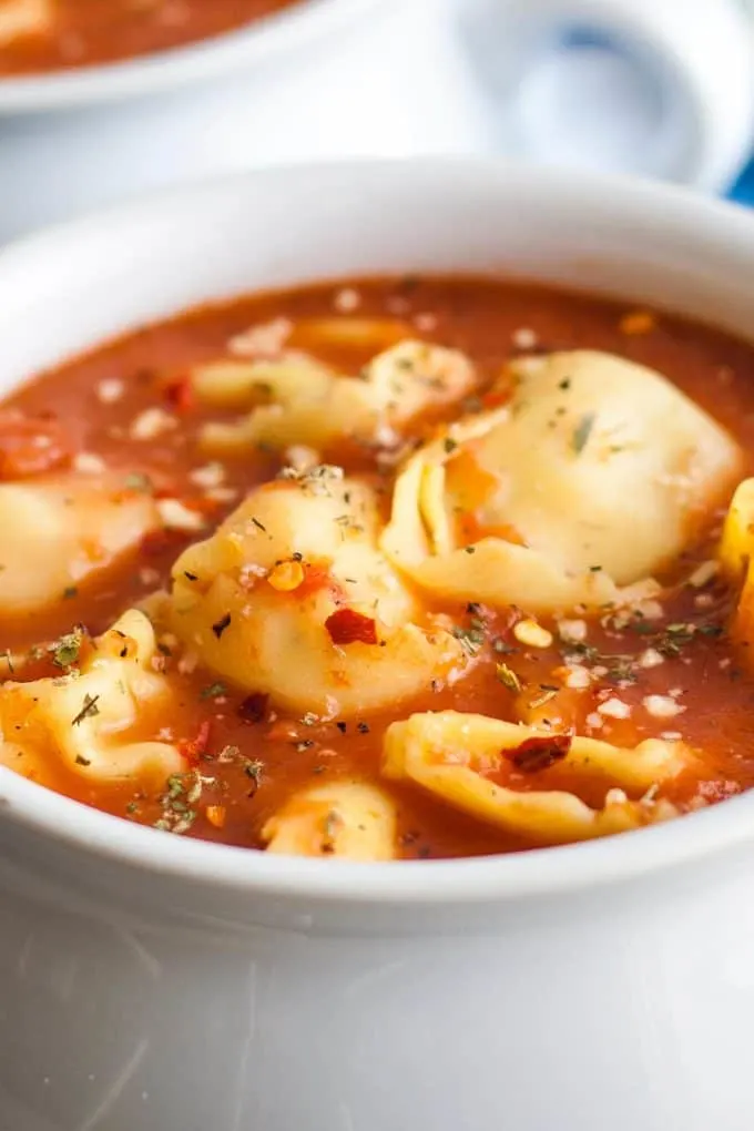 one white bowl full of tomato tortellini soup