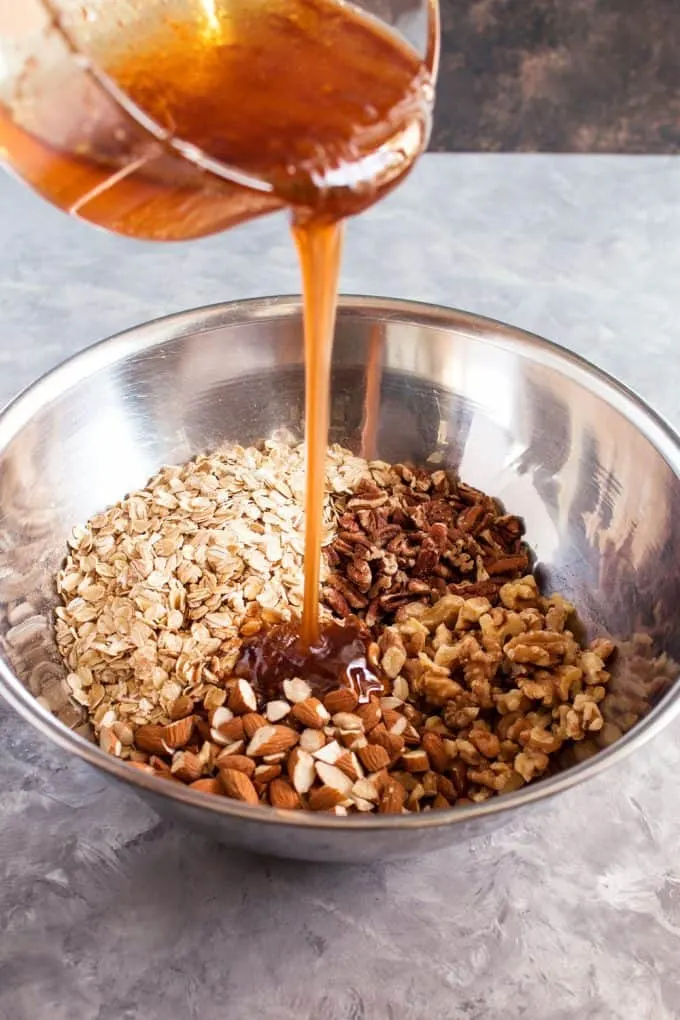 honey and oil mixture being added to dry granola ingredients