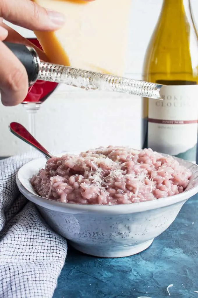 parmesan being grated over red wine risotto