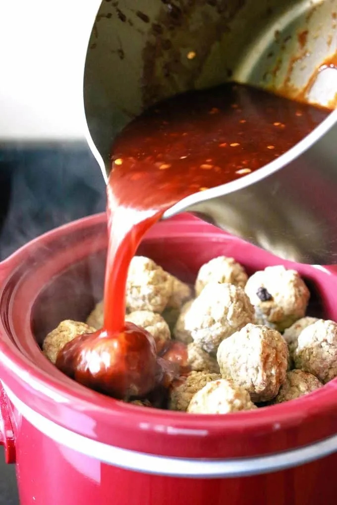 chili pepper jelly sauce being poured on top of frozen meatballs
