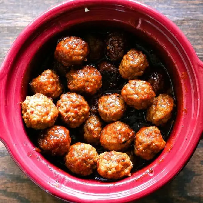 cooked sweet and spicy meatballs in a red crockpot