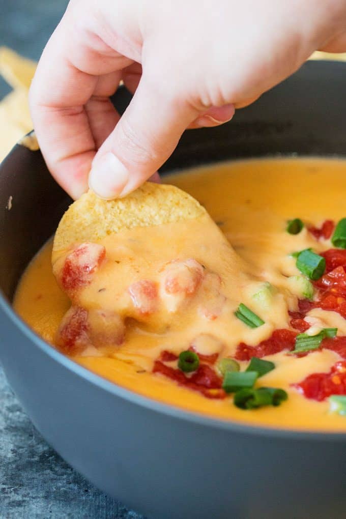 dipping chip into tomato queso dip