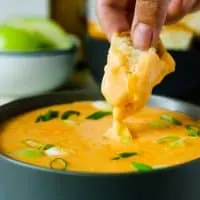 piece of bread being dipped into beer cheese dip