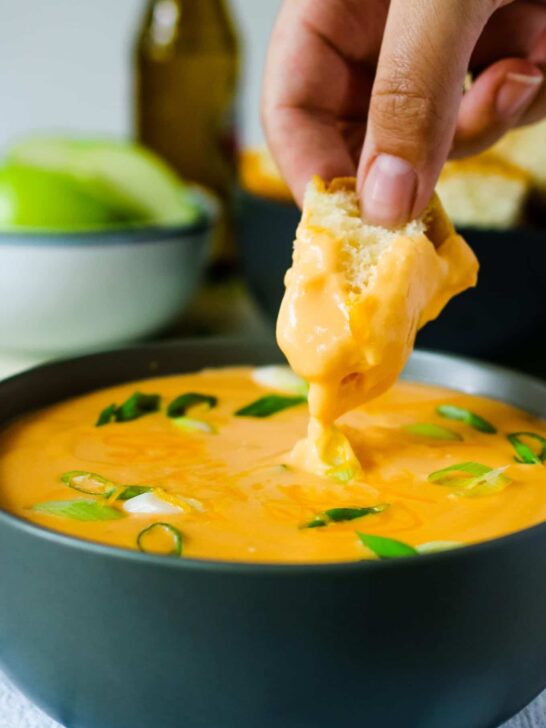 piece of bread being dipped into beer cheese dip