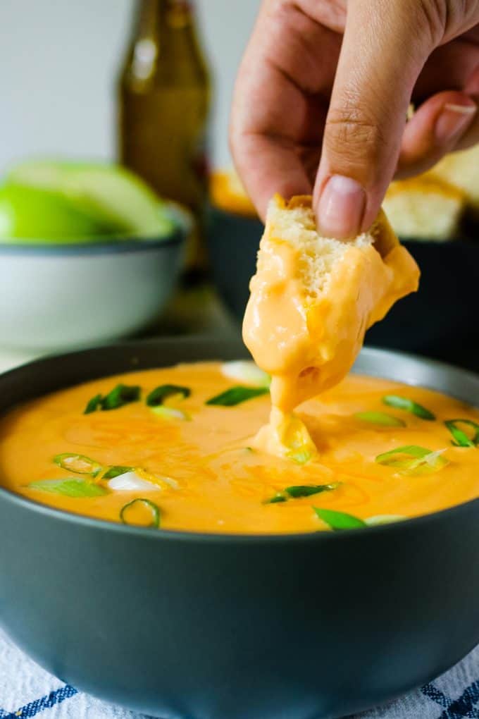 piece of bread being dipped into beer cheese dip