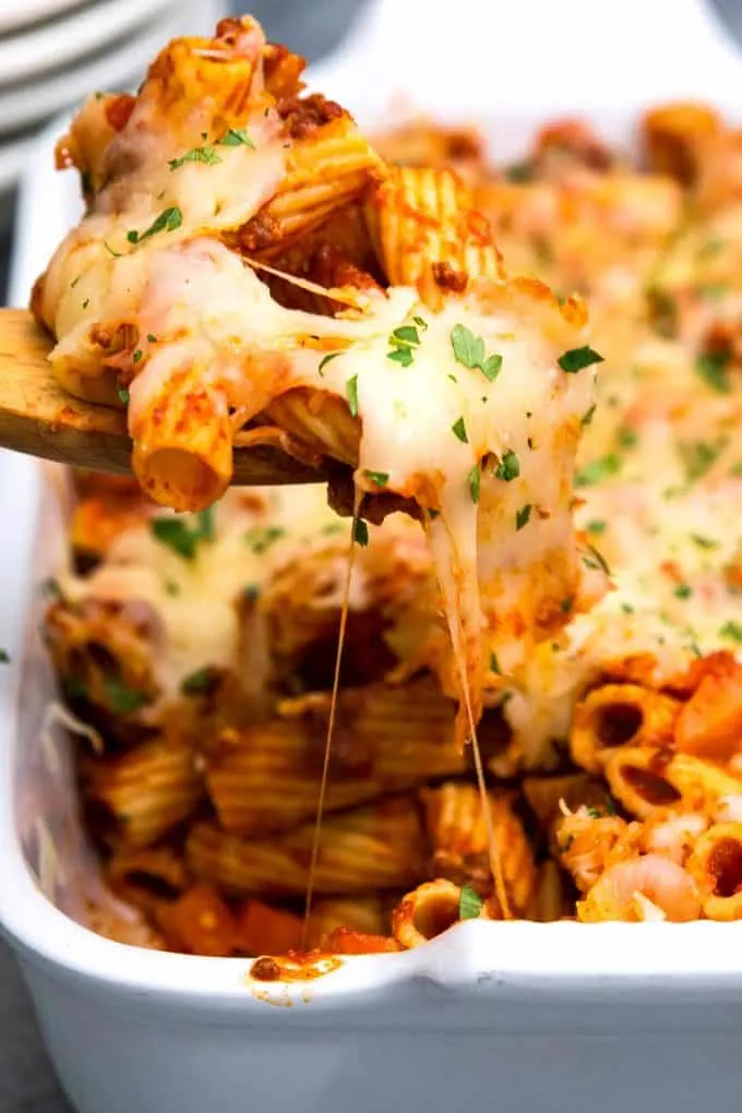 scoop of pasta being taken out of casserole dish cheese pull