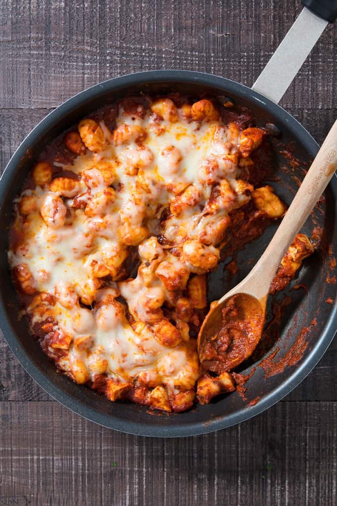 one pan cheesy gnocchi in a pan with a wooden spoon