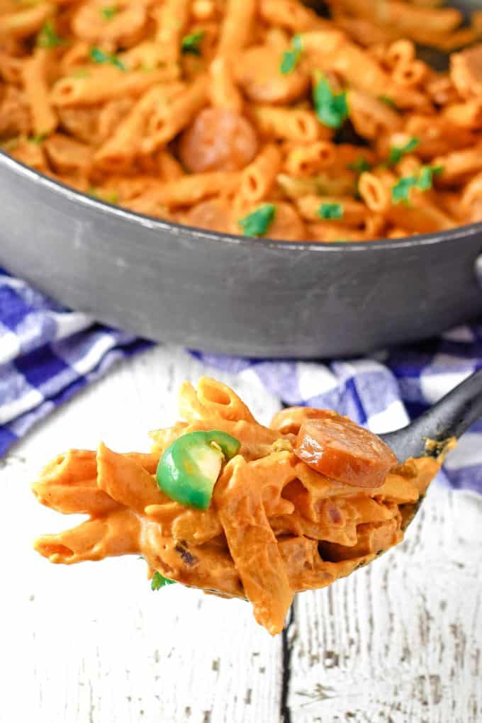 black spoon filled with spicy sausage pasta and jalapeÃ±os