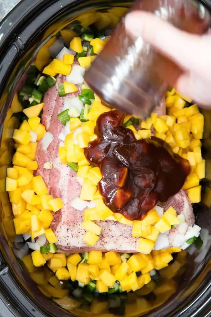 bbq sauce being added to a slow cooker