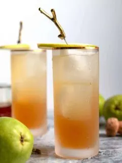 two sparkling bourbon pear cocktails with pear garnishes