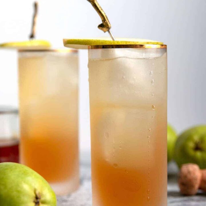 two sparkling bourbon pear cocktails with pear garnishes