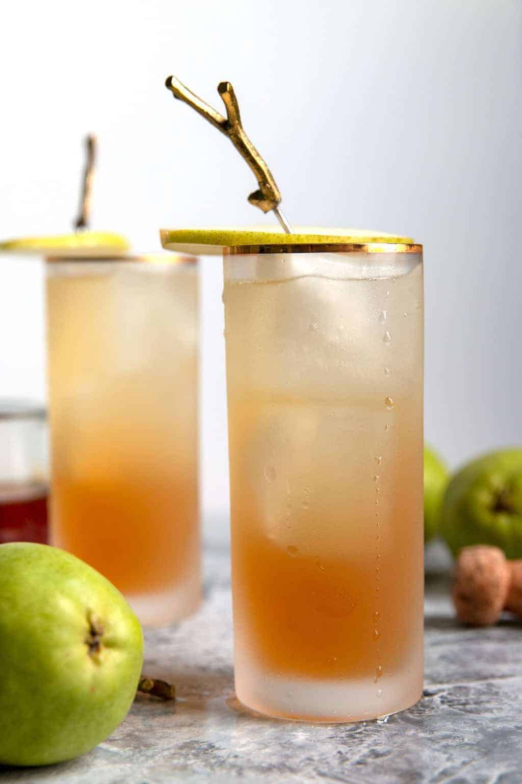 two sparkling bourbon pear cocktails with pear garnishes