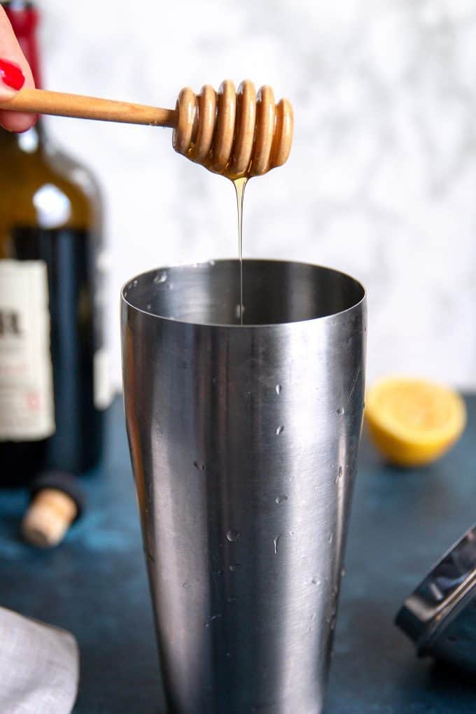 honey being dripped into a cocktail shaker