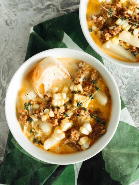 two bowls of spicy sausage corn chowder with a green napkin