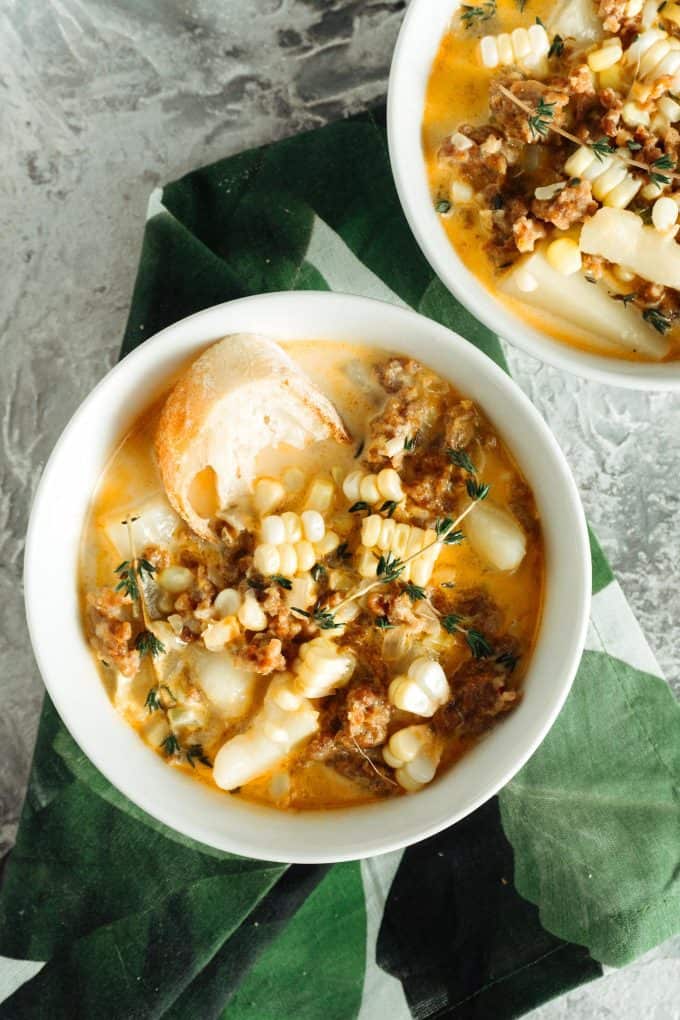 two bowls of spicy sausage corn chowder with a green napkin