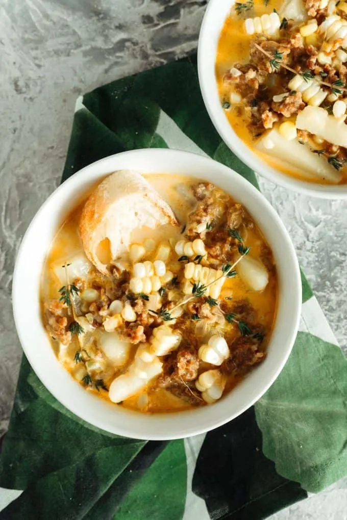 two bowls of spicy sausage corn chowder with a green napkin