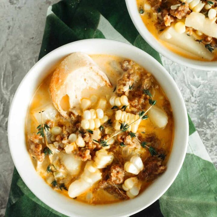 two bowls of spicy sausage corn chowder with a green napkin