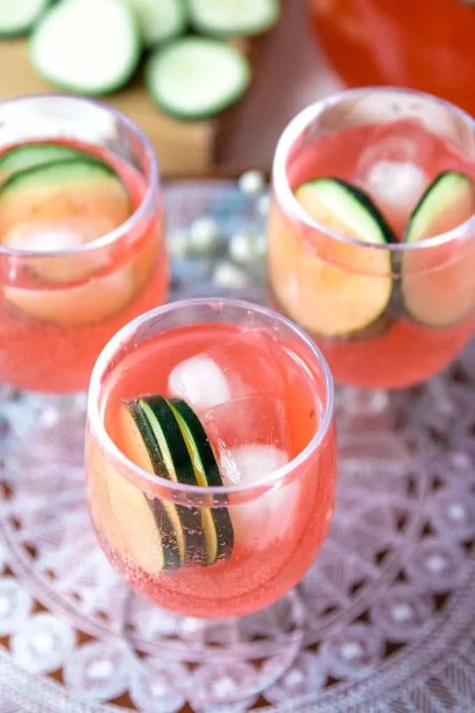 three glasses of cucumber watermelon punch on a patterned cutting board