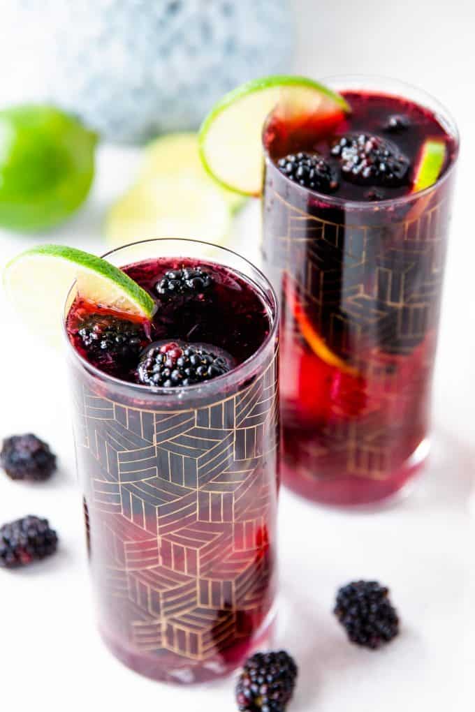 two glasses blackberry sangria garnished with lime slices