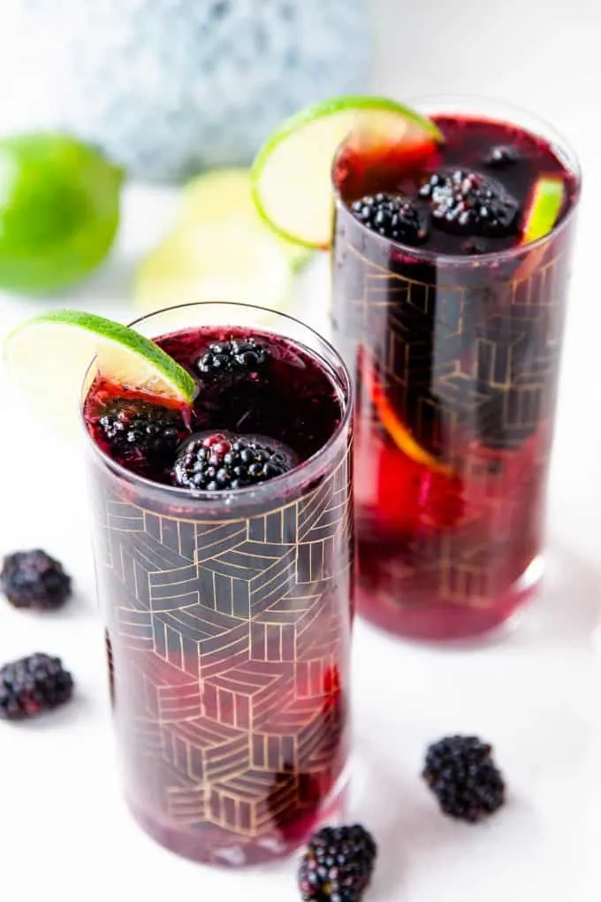 two glasses blackberry sangria garnished with lime slices