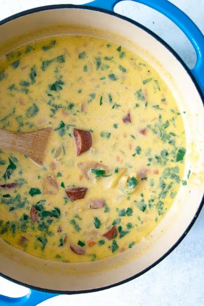 potato kielbasa soup in a dutch oven with a wooden spoon