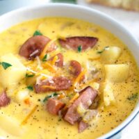 white bowl of potato kielbasa soup garnished with cheese