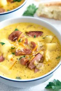 white bowl of potato kielbasa soup garnished with cheese