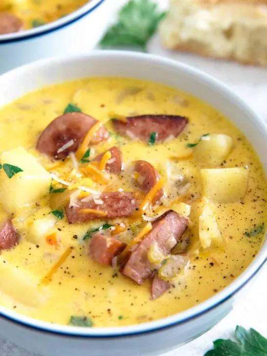 white bowl of potato kielbasa soup garnished with cheese