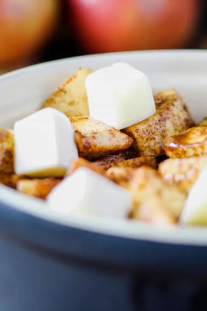 closeup of cut cubed butter on unbaked spiced apples