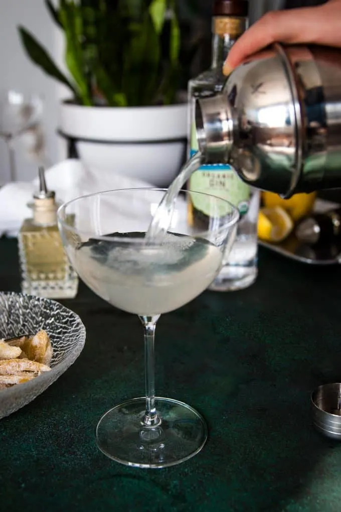 straining a gin ginger martini into a martini glass