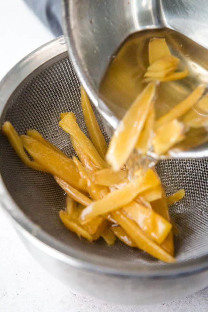 straining the ginger simple syrup from the cooked ginger pieces