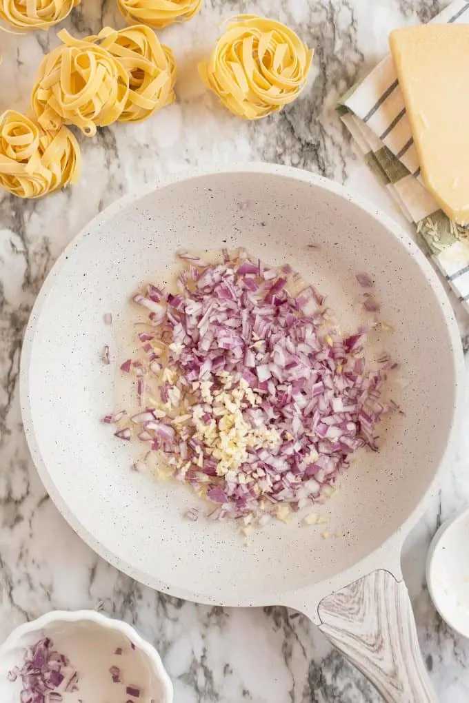 diced red onion, olive oil, and garlic in a pan, about to be sautéed