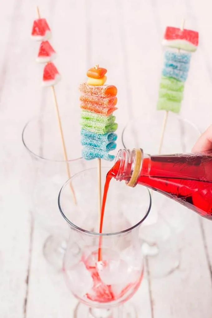 grenadine being poured into a glass with ice