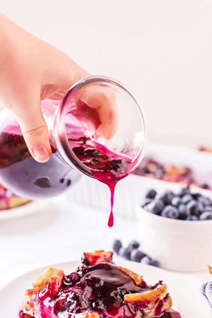 pouring blueberry syrup on pancakes