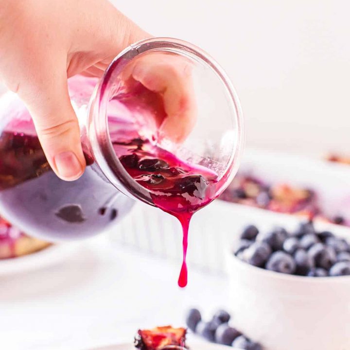 pouring blueberry syrup on pancakes