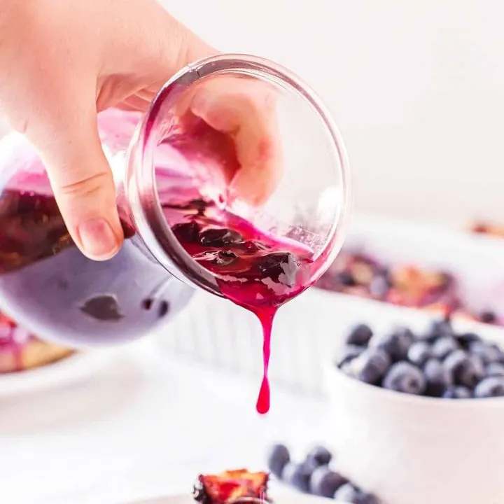 pouring blueberry syrup on pancakes