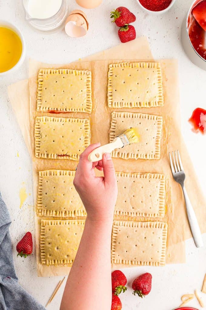 brushing egg wash on top of all of the unbaked homemade pop tarts