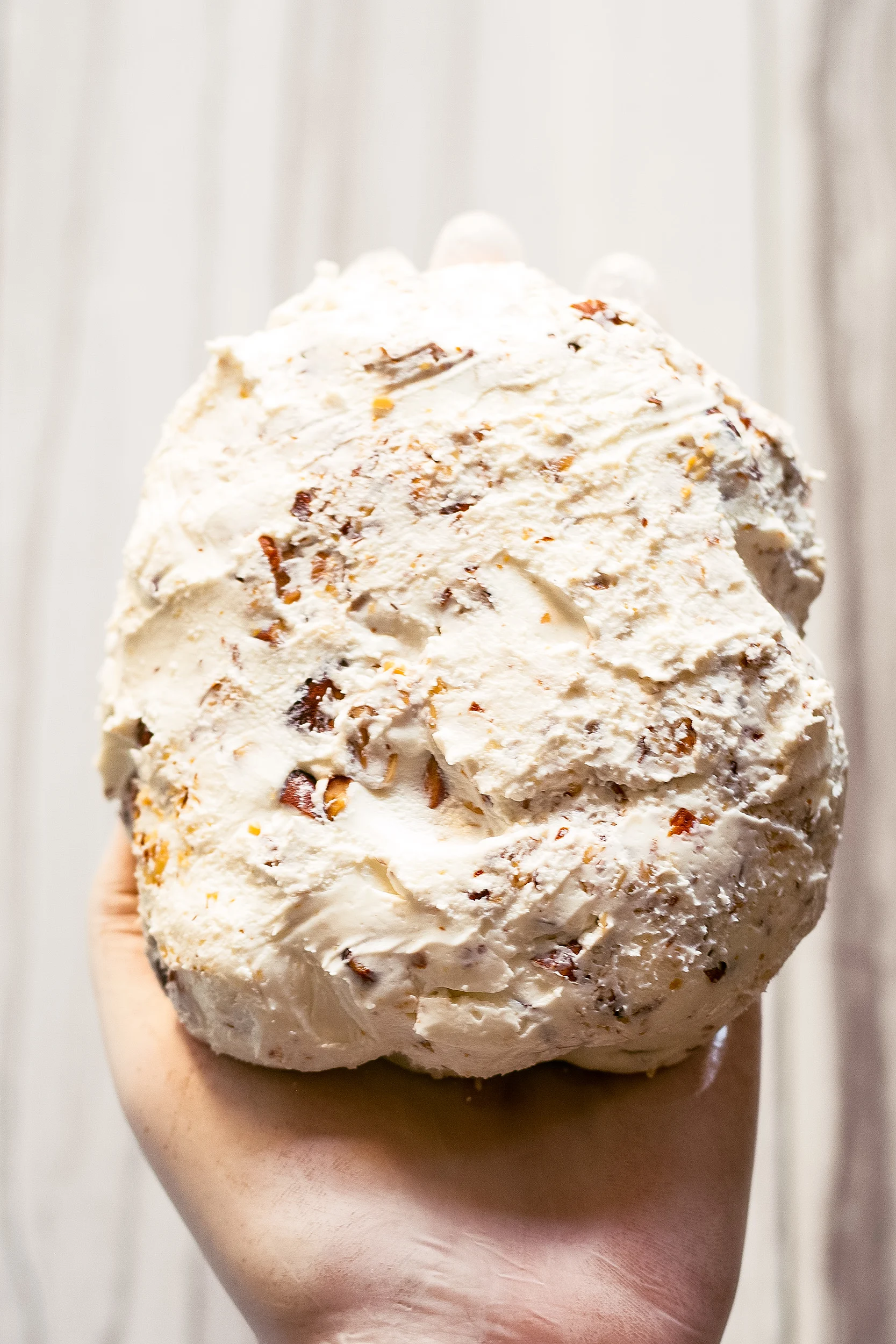 goat cheese ball with almonds in the palm of a hand