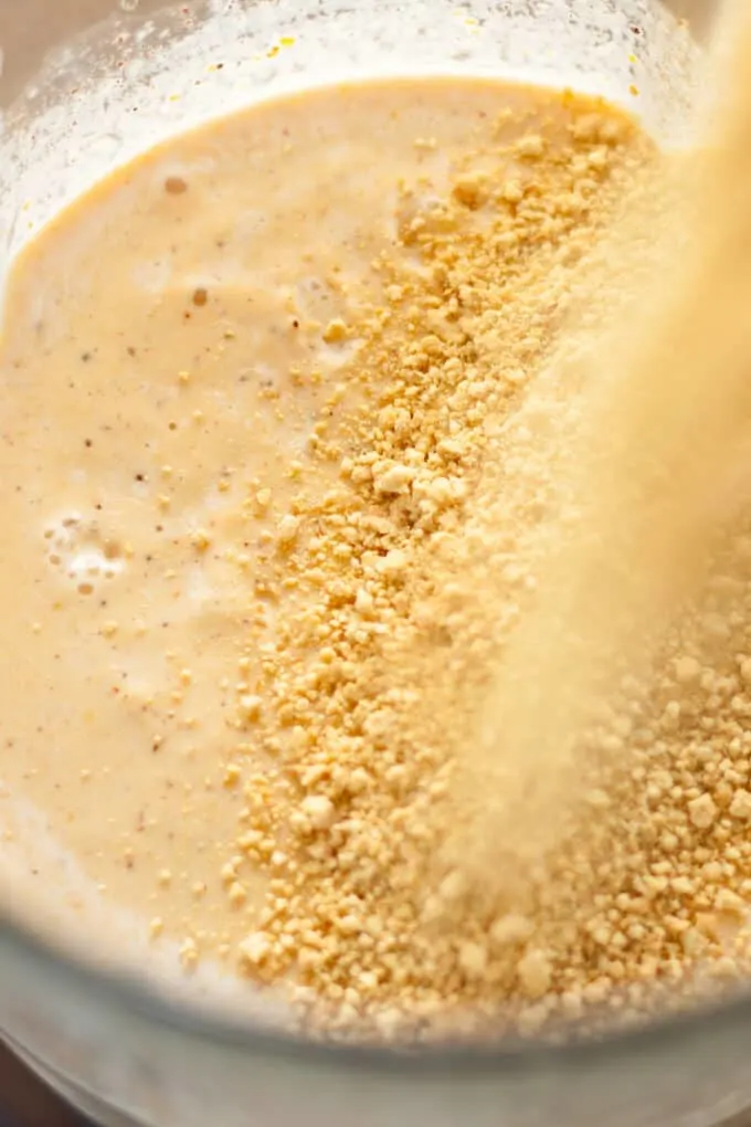 graham cracker crumbs being poured into the blended milkshake, in the blender