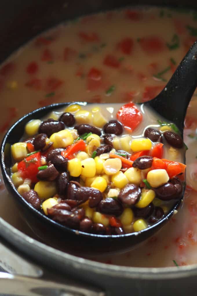 pot of black bean corn chowder with a ladle full of the soup hovering above