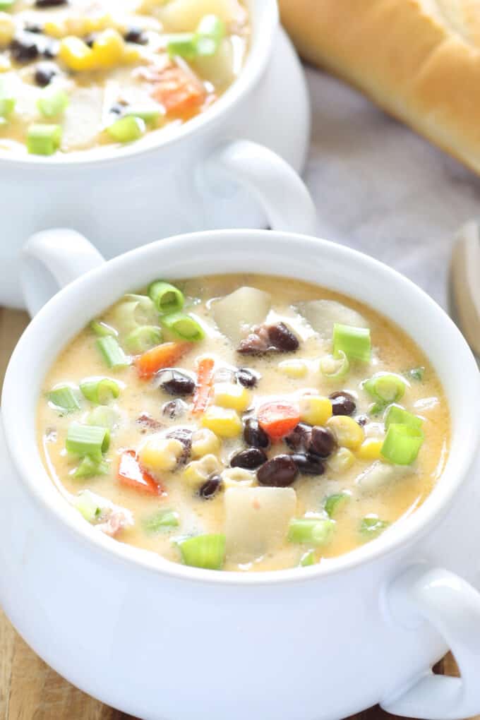 two white soup bowls of chowder with fresh green onions as garnish