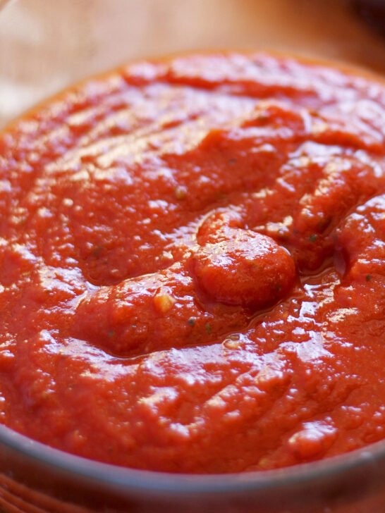 pizza sauce with specks of minced garlic in a clear glass bowl