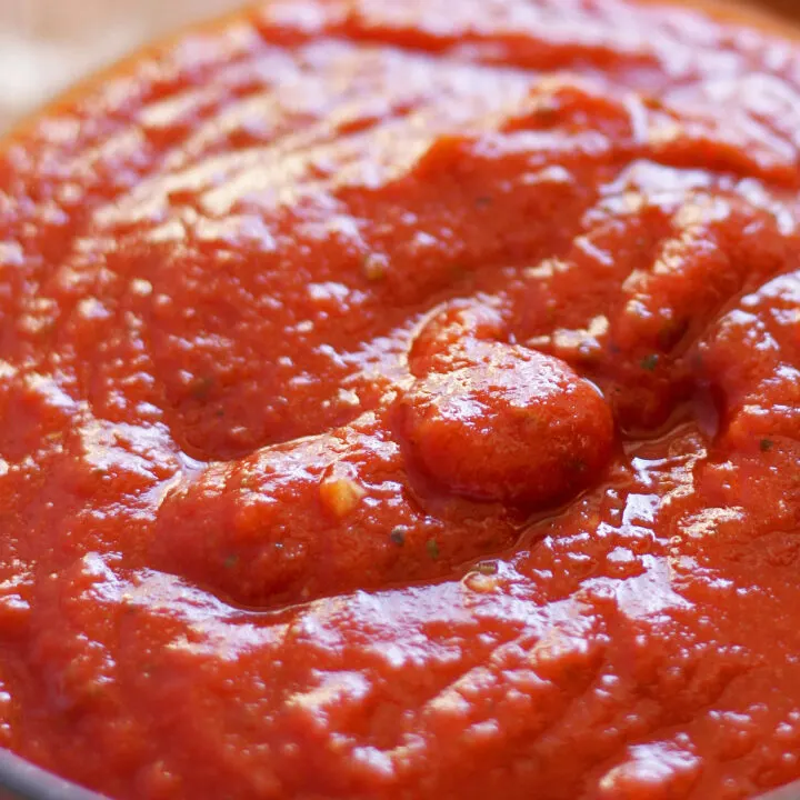 pizza sauce with specks of minced garlic in a clear glass bowl