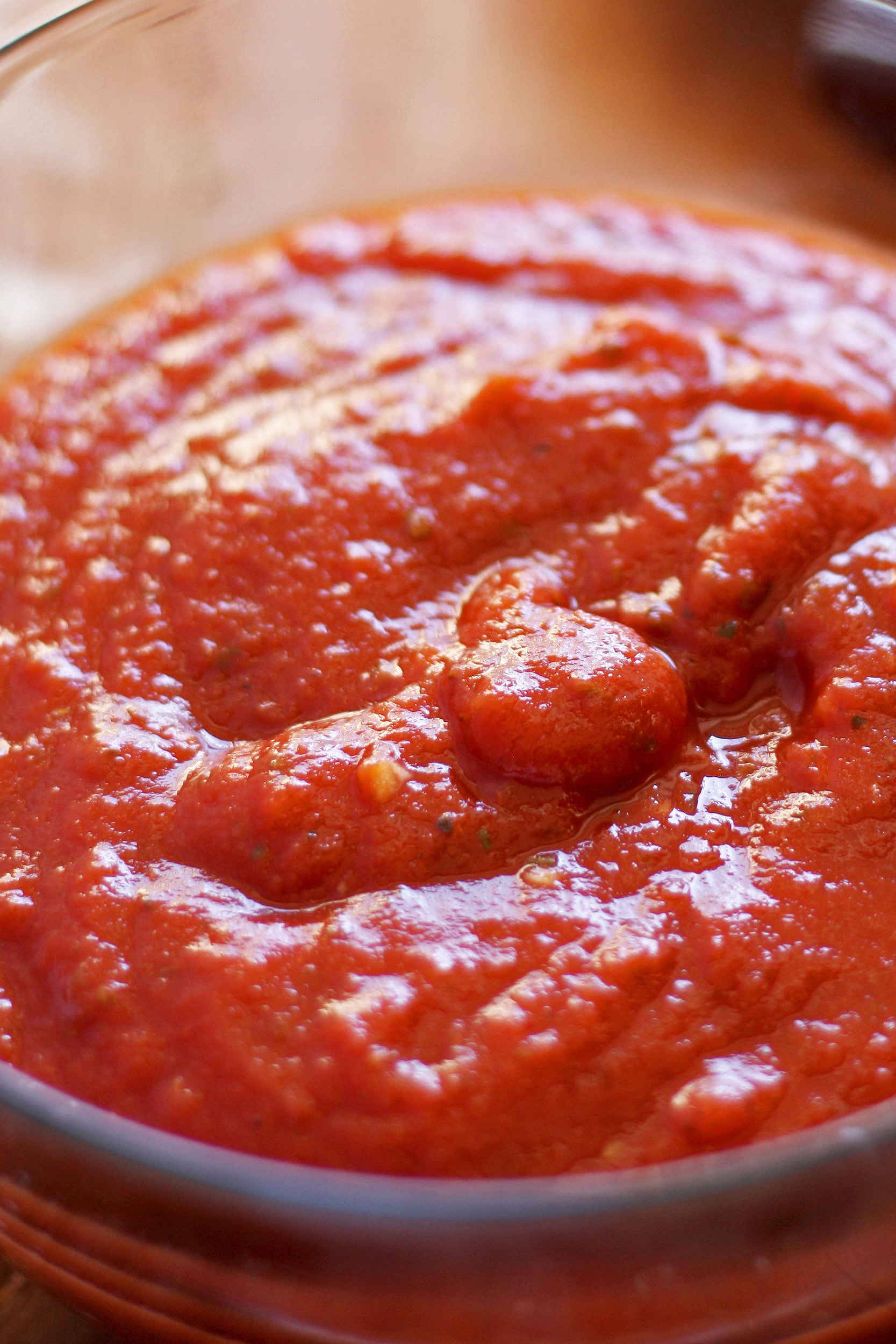 pizza sauce with specks of minced garlic in a clear glass bowl