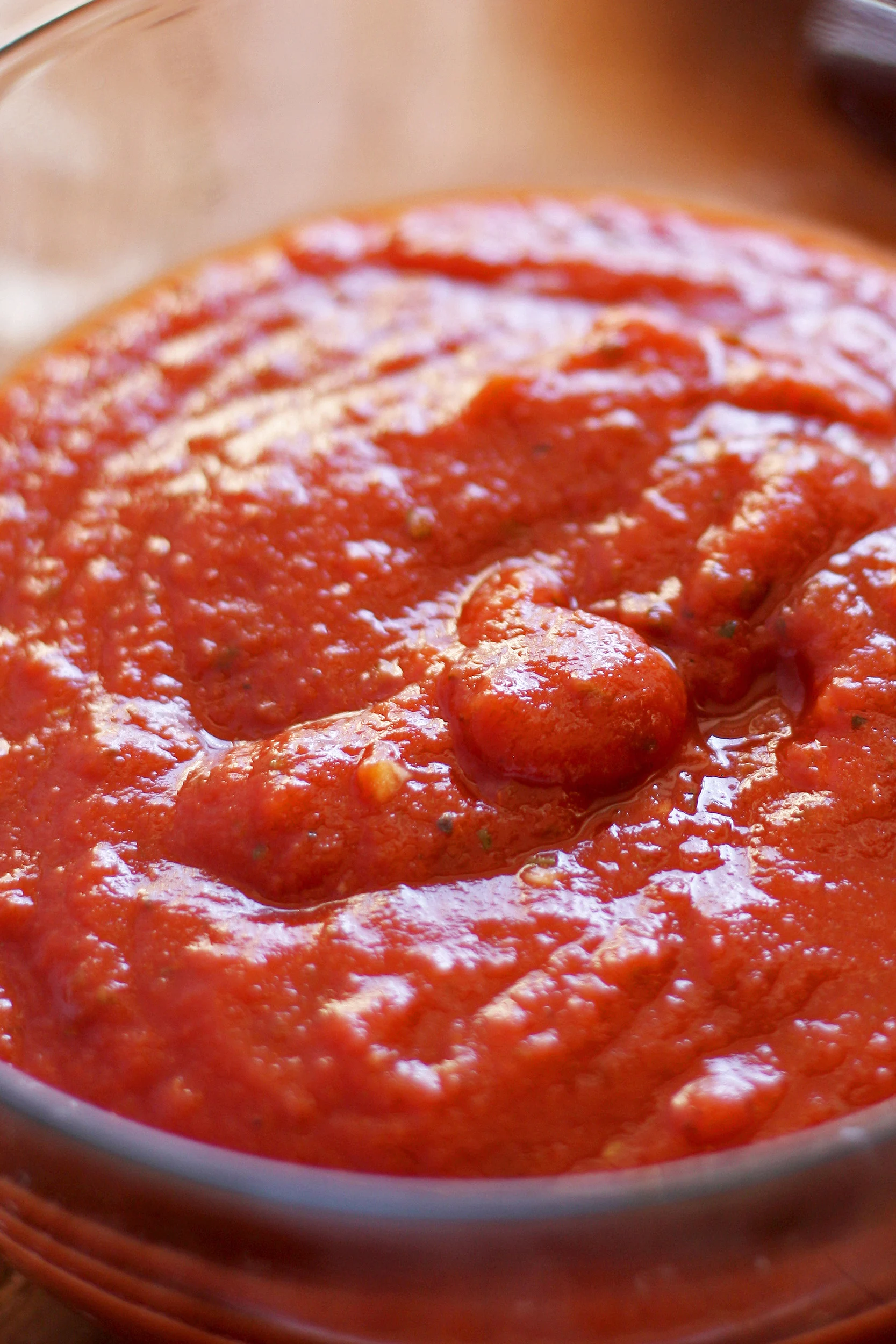 pizza sauce with specks of minced garlic in a clear glass bowl