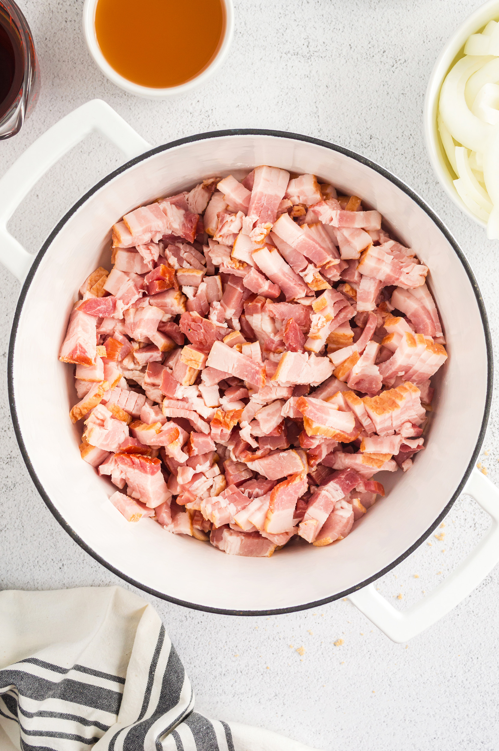 uncooked bacon, cut into ½ inch pieces, in a white large pot