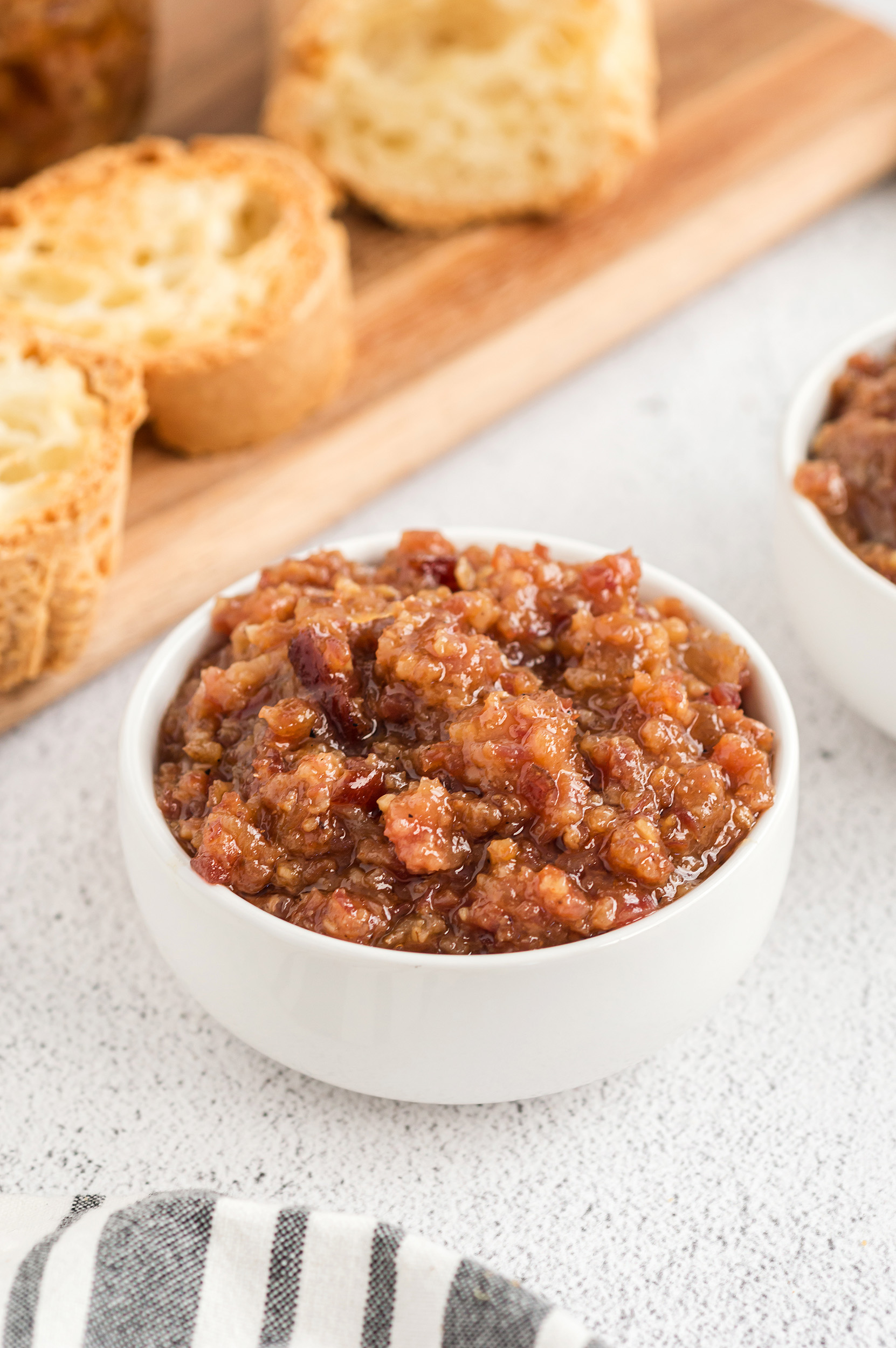 white bowl of homemade bacon marmalade next to toasted crostini